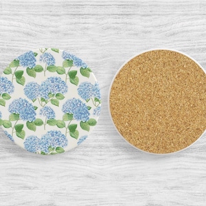 May include: Two round coasters, one with a blue and green floral pattern and the other with a cork surface.