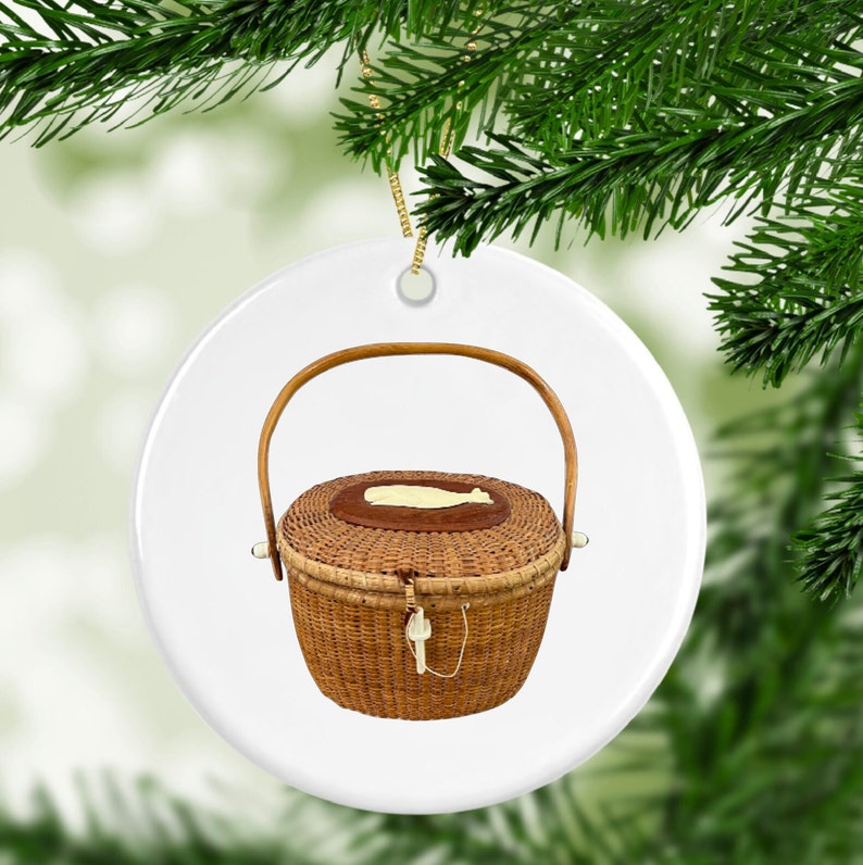 May include: A white ceramic Christmas ornament featuring a brown wicker basket with a handle and a white whale design on the lid.