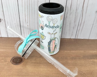 May include: White insulated tumbler with a black rim, featuring golf-themed illustrations and the name "Amanda" in teal. Includes a clear straw and a teal ribbon. The tumbler is designed to hold a standard 12 oz can.