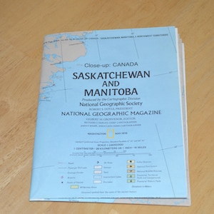 May include: A blue map of Saskatchewan and Manitoba, Canada, produced by the National Geographic Society. The map is titled "Close-up: Canada Saskatchewan and Manitoba" and includes the text "National Geographic Magazine".