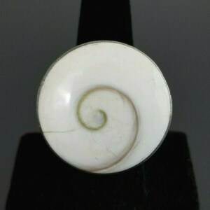 Op de afbeelding: Een witte schelp ring met een zilveren zetting. De schelp heeft een spiraalvormig patroon in het midden.