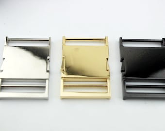 May include: Three metal buckles in silver, gold, and black. Each buckle has a rectangular frame with a sliding mechanism and a central bar. The buckles are designed for use in various crafting and sewing projects.