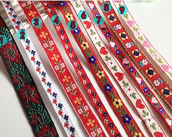 May include: Nine different embroidered ribbon trims with various floral and heart designs. The ribbons are red, white, black, and cream with colorful embroidery.