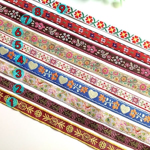 K&ouml;nnte beinhalten: Neun verschiedene B&auml;nder aus farbigem besticktem Band mit Blumen- und Herzmotiven. Die B&auml;nder sind von 1 bis 9 nummeriert.