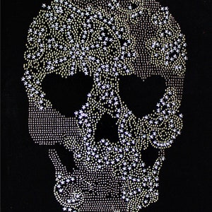 Puede incluir: Un diseño de calavera negra hecho con pedrería plateada y dorada. La calavera mide aproximadamente 31 cm por 21 cm.