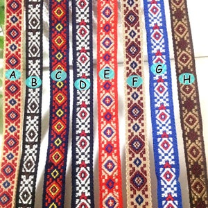 Op de afbeelding: Acht verschillende gepatroneerde trimstroken in verschillende kleuren, waaronder rood, blauw, wit, bruin en beige. De trim is geweven met een geometrisch ontwerp.