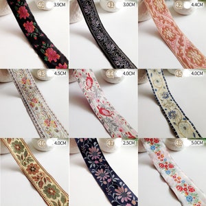 Könnte beinhalten: Sortiment von acht bestickten Besatzbändern in verschiedenen Farben und Mustern. Die Bänder sind etwa 4 cm breit und zeigen florale, geometrische und abstrakte Designs.