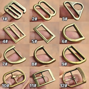 May include: Twelve different styles of metal buckles in antique gold finish. The buckles are arranged in rows of three. Each buckle is labeled with a number from 1 to 12.