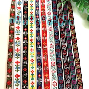 Könnte beinhalten: Elf verschiedene Bänder mit bunten Mustern und floralen Designs. Die Bänder sind von 1 bis 11 nummeriert.