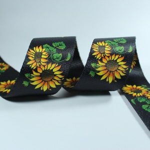 May include: Black ribbon with a repeating pattern of yellow sunflowers and green leaves.