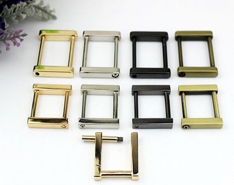May include: Eight metal D-rings in four different finishes: gold, silver, black, and antique brass. The rings are all the same size and shape, and they are arranged in two rows of four. There is also a single, smaller D-ring in gold.