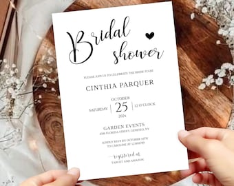 Puede incluir: Una invitación de despedida de soltera blanca con texto negro. La invitación dice "Bridal Shower" con un pequeño corazón negro. El nombre de la novia es Cynthia Parquer. La despedida de soltera está programada para el sábado 25 de octubre de 202x a las 12 en punto. El evento se llevará a cabo en Garden Events, 4506 Florida Street, Geneseo, NY. Confirma tu asistencia antes del 19 de octubre a Caroline al 123456719. La invitación también indica que la pareja está registrada en Target y Amazon.
