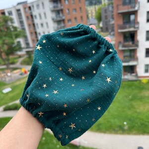 Pode incluir: Um bloomers de bebê de tecido verde escuro com estampa de estrelas douradas.