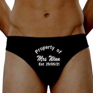 May include: Black briefs with the white text "Property of Mrs Winn Est 29/05/21". The underwear is a brief style.