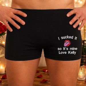 Puede incluir: Calzoncillos tipo bóxer negros con texto en blanco que dice I sucked it so it's mine Love Kelly, acompañado de un gráfico de labios rojos con una lengua morada. La prenda tiene un color base negro sólido y una cintura elástica estándar.