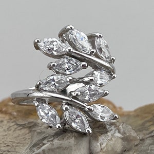 Può includere: Un anello d'argento con un design di pietre chiare a forma di marquise incastonate in un motivo a foglia.