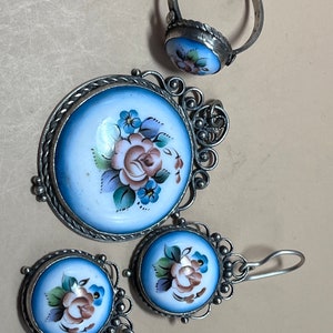 Peut inclure: Un ensemble de bijoux en argent avec des motifs floraux en &eacute;mail bleu et blanc. L'ensemble comprend une bague, un pendentif et une paire de boucles d'oreilles.
