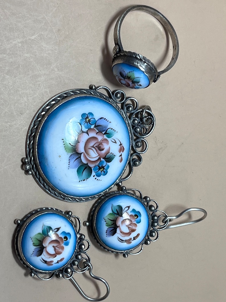 Peut inclure: Un ensemble de bijoux en argent avec des motifs floraux en &eacute;mail bleu et blanc. L'ensemble comprend une bague, un pendentif et une paire de boucles d'oreilles.