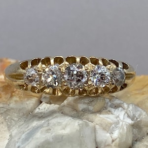 May include: A gold band ring with four round diamonds set in a row.