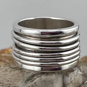 May include: A silver ring made of multiple stacked bands. The ring is smooth and shiny.