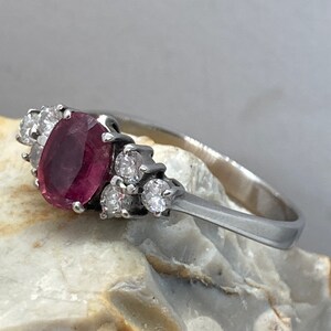 May include: A silver ring with a pink oval gemstone surrounded by smaller clear gemstones.