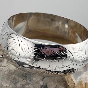 Peut inclure: Un bracelet en argent avec un motif floral gravé sur la surface.