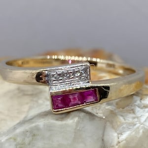 Op de afbeelding: Een gouden ring met een roze robijn en kleine diamanten gezet in een witgouden band.