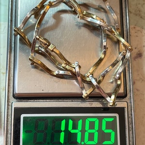 Op de afbeelding: Een gouden en zilveren kettingarmband op een digitale weegschaal. De weegschaal geeft 9,485 gram aan.