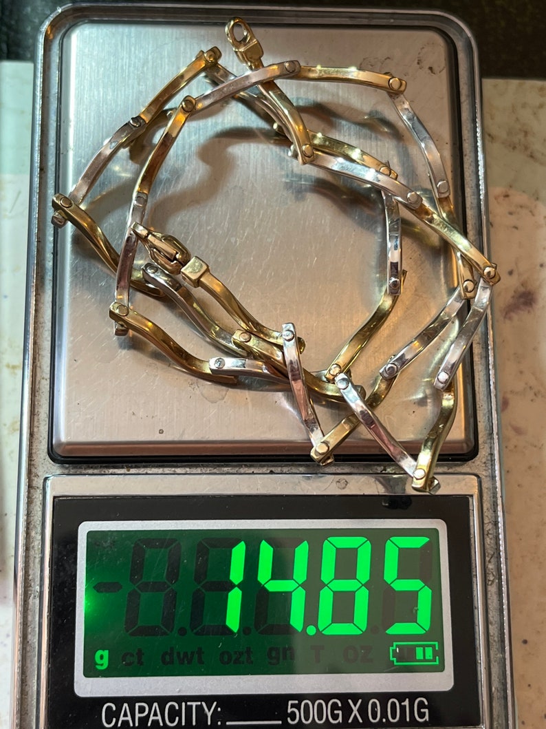 Op de afbeelding: Een gouden en zilveren kettingarmband op een digitale weegschaal. De weegschaal geeft 9,485 gram aan.