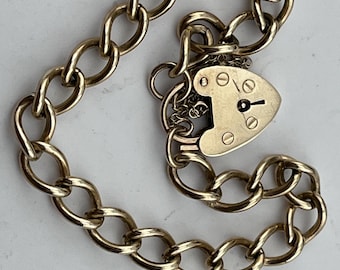 May include: A gold chain bracelet with a heart-shaped padlock charm. The chain is made of oval links.