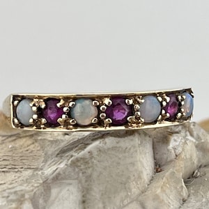 May include: A silver band ring with alternating opal and purple gemstones.