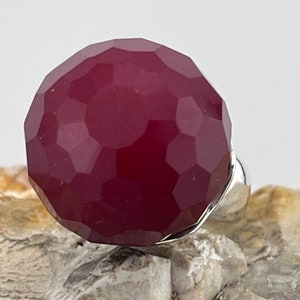 May include: A faceted, burgundy-coloured gemstone ring with a silver band.