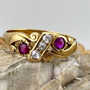 以下が含まれることがあります： ルビーとダイヤモンドがセットされた金の指輪。指輪は繊細で装飾的なデザインです。