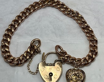 May include: A gold chain bracelet with a heart-shaped padlock and a heart-shaped charm. The padlock has a keyhole and the charm has a detailed design.