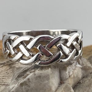 May include: A silver Celtic knot ring with a braided design.