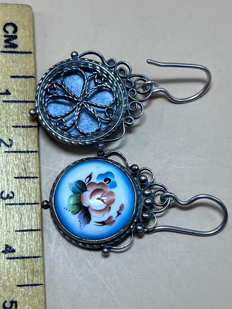 Peut inclure: Une paire de boucles d'oreilles en argent avec un motif de fleur en porcelaine bleue et blanche. Les boucles d'oreilles ont un design en filigrane et une fermeture &agrave; crochet.