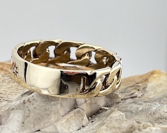 May include: A gold ring with a chain-link design. The ring has a small star-shaped stone set into the band.