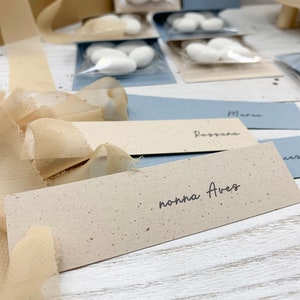 Semplici Segnaposti battesimo con nome invitato in due varianti colore: tortora e carta da zucchero