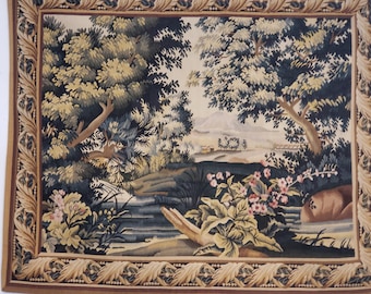 May include: A tapestry with a detailed depiction of a forest scene. The tapestry features a stream flowing through the forest, with trees and flowers on either side. The background shows a distant mountain range.