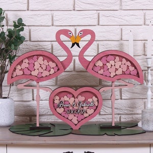 Pode incluir: Caixa de cartão de casamento de flamingo rosa com uma abertura em forma de coração. A caixa é decorada com corações rosa e o texto "Brian & Gabrielle 5/30/2021".