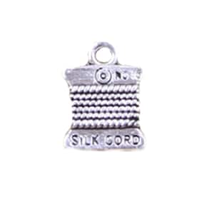 May include: A silver charm in the shape of a spool of thread with the words "SILK CORD" engraved on the front.