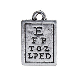 May include: A small, rectangular silver-toned charm featuring a miniature eye chart. The chart displays the letters E, FP, TOZ, and LPED in descending order. The charm has a loop at the top for attachment.