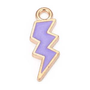 May include: A gold-colored charm with a purple lightning bolt design. The charm has a loop at the top for attaching to a necklace or bracelet.