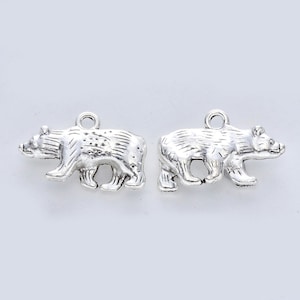 May include: Two silver bear charms, each with a loop for attaching to a necklace or bracelet. The bears are facing to the right and have a detailed, realistic design.