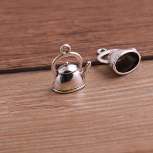 May include: Two silver-toned teapot charms with a loop for attaching to a necklace or bracelet.
