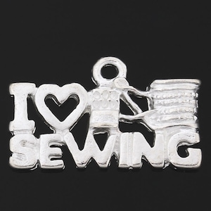 May include: Silver charm with the words "I love sewing" and a sewing machine design.