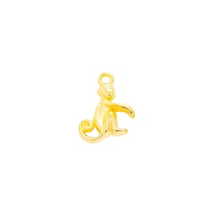 May include: Gold-colored monkey charm pendant. The monkey is sitting with its tail curled around its legs.