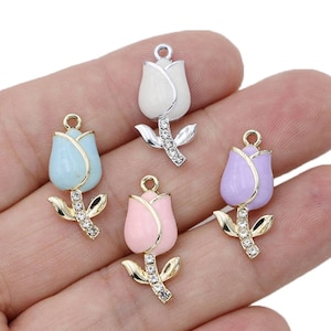 May include: Four enamel flower charms with rhinestone accents. The charms are in the shape of a tulip with a gold or silver finish. The colors are white, light blue, pink, and purple.