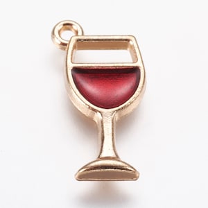May include: Gold-toned metal charm shaped like a wine glass filled with red enamel. The charm has a loop at the top for attaching to a necklace or bracelet.