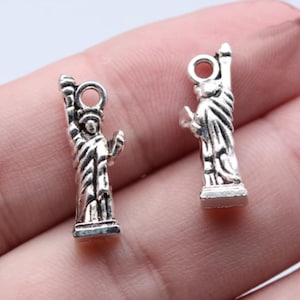 May include: Two silver-toned charms shaped like the Statue of Liberty. The charms are detailed and have a vintage look.